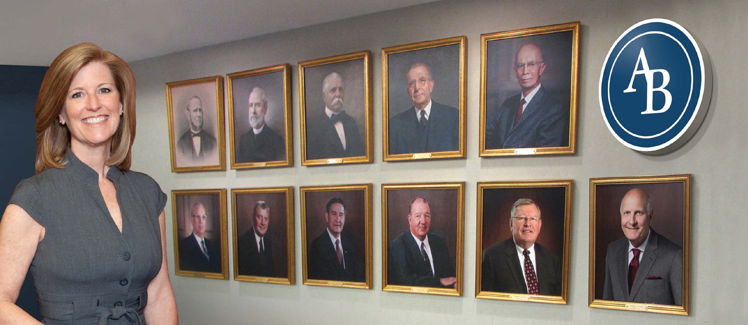 President in front of past president photo wall